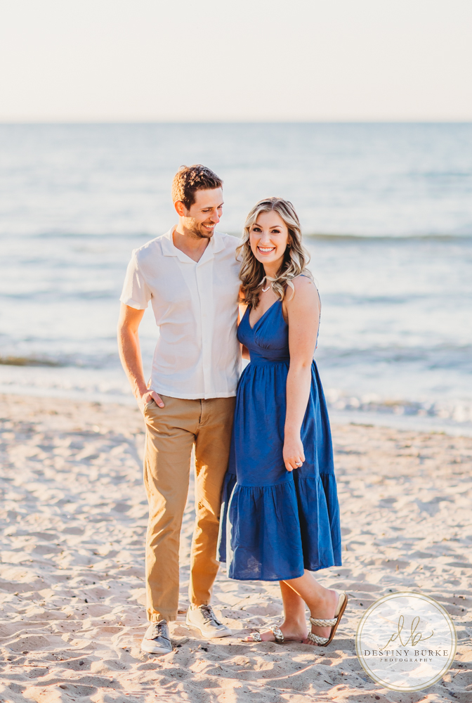Engagement Session with Couple at Durand Eastman Beach in Irondequoit, NY near Rochester at sunset with champagne toast, engagement ring
