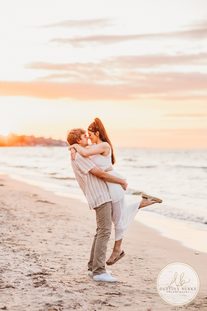 Durand Eastman Park in Irondequoit, NY, Couple poses for Engagement portrait photography session at sunset on the beach , portraits done by Destiny Burke Photography