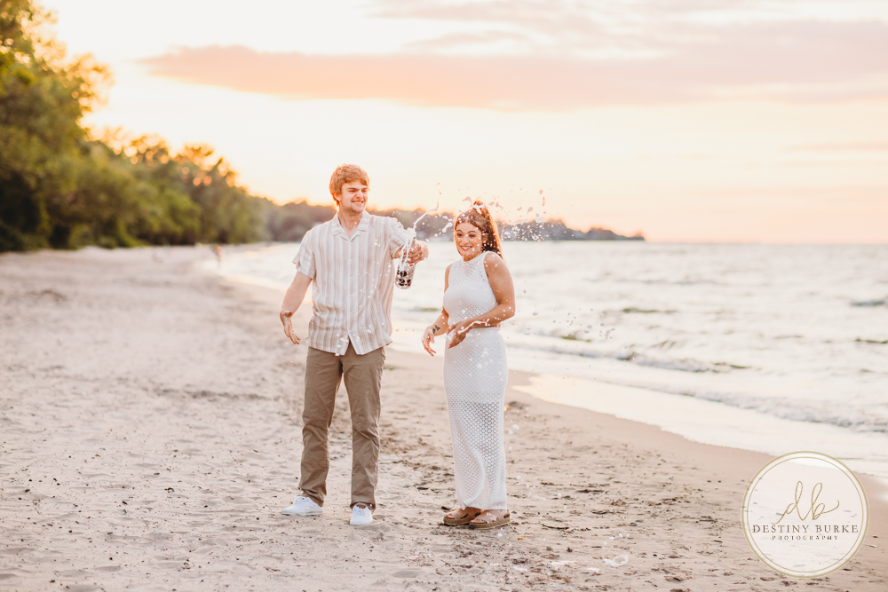 Durand Eastman Park in Irondequoit, NY, Couple poses for Engagement portrait photography session at sunset on the beach , portraits done by Destiny Burke Photography