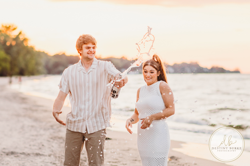 Durand Eastman Park in Irondequoit, NY, Couple poses for Engagement portrait photography session at sunset on the beach , portraits done by Destiny Burke Photography