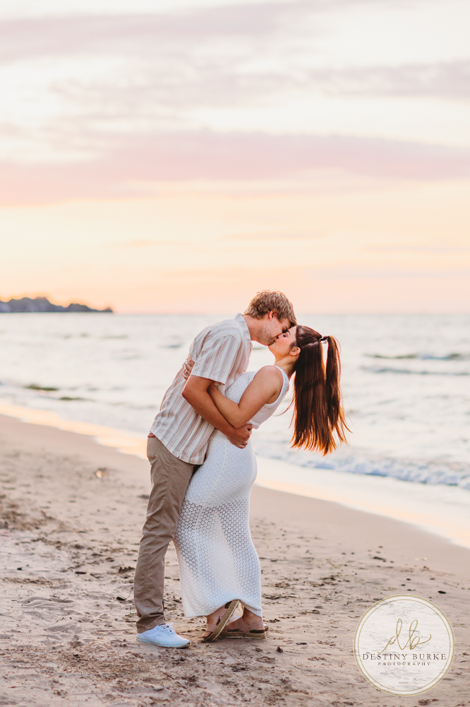 Durand Eastman Park in Irondequoit, NY, Couple poses for Engagement portrait photography session at sunset on the beach , portraits done by Destiny Burke Photography
