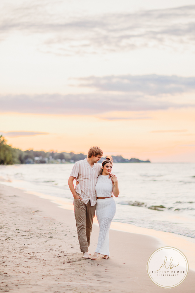 Durand Eastman Park in Irondequoit, NY, Couple poses for Engagement portrait photography session at sunset on the beach , portraits done by Destiny Burke Photography