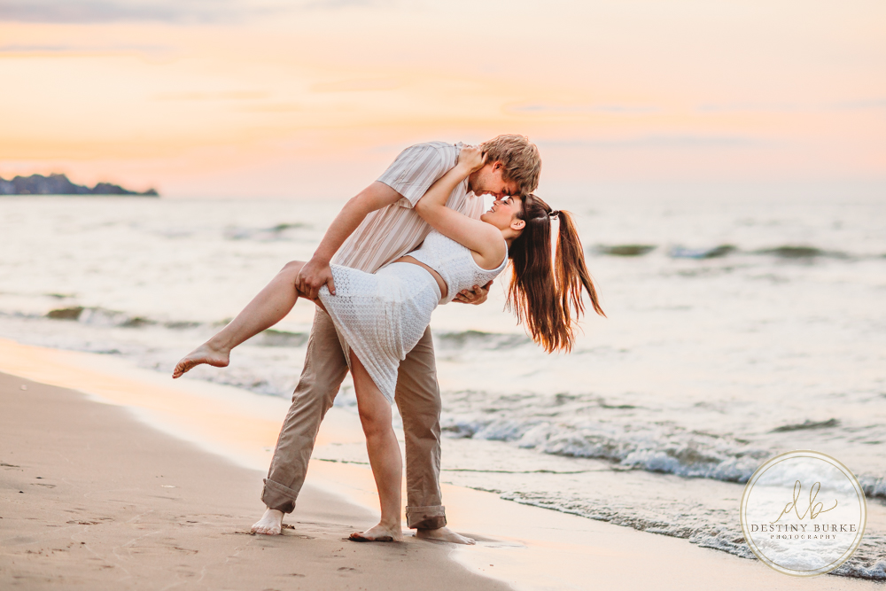 Durand Eastman Park in Irondequoit, NY, Couple poses for Engagement portrait photography session at sunset on the beach , portraits done by Destiny Burke Photography