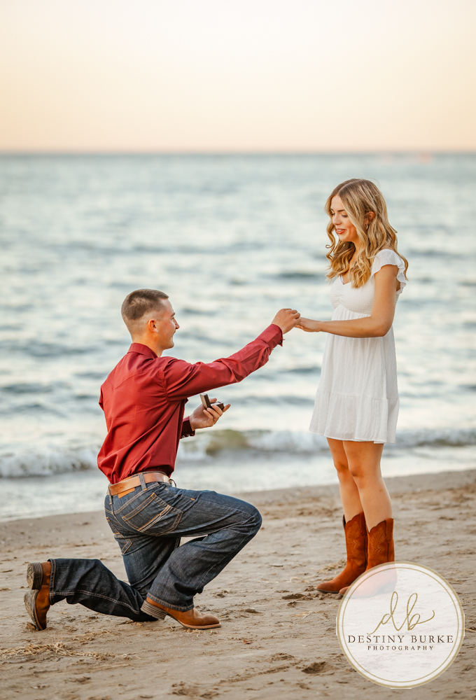 Surprise beach proposal at Durand Eastman Beach near Rochester, NY, captured by the best surprise proposal photographer near Rochester, NY during golden hour along Lake Ontario.