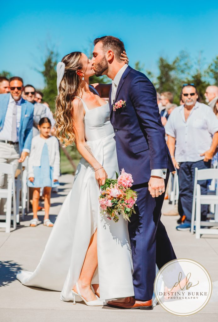 ride and groom sharing first kiss after wedding ceremony at Pomona at Blue Barn Hilton NY