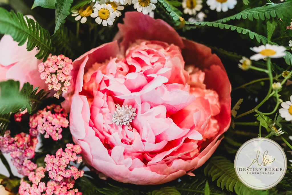 Bride's diamond engagement ring resting inside a pink peony bouquet at Pomona at Blue Barn wedding