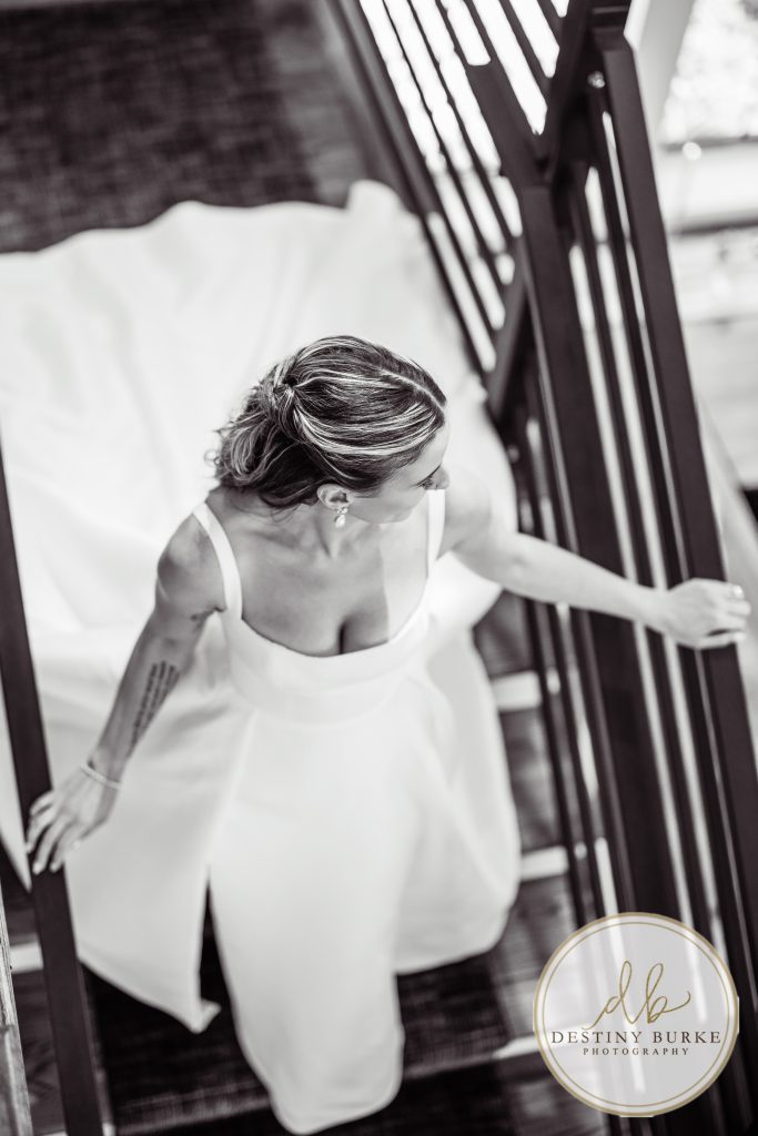 Bride walking down staircase in elegant wedding gown at Pomona at Blue Barn Hilton NY