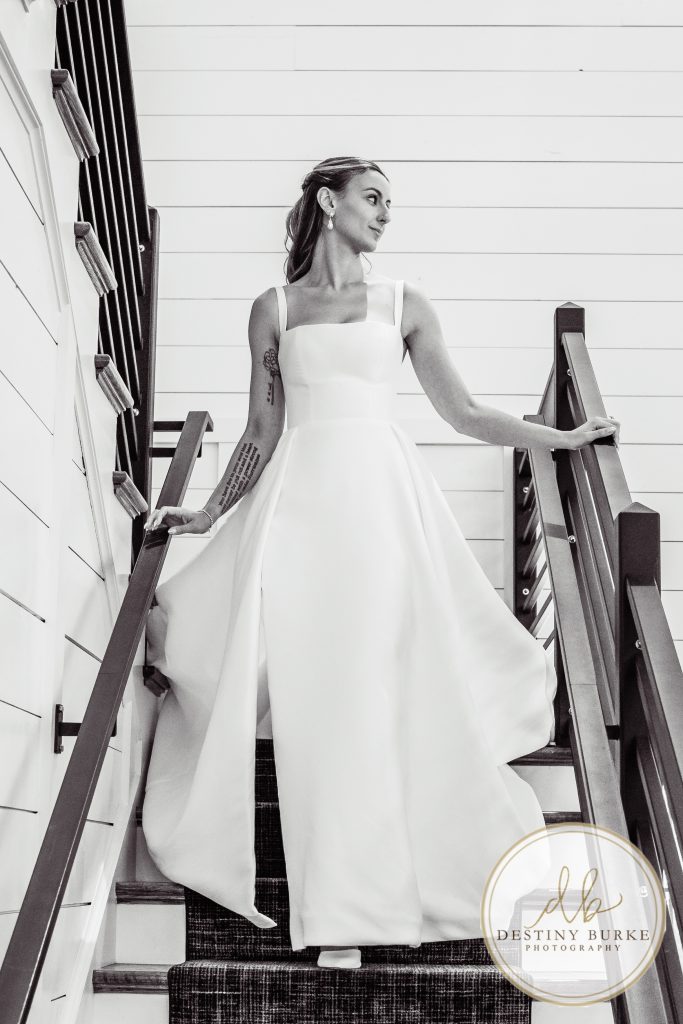 Bride walking down staircase in elegant wedding gown at Pomona at Blue Barn Hilton NY